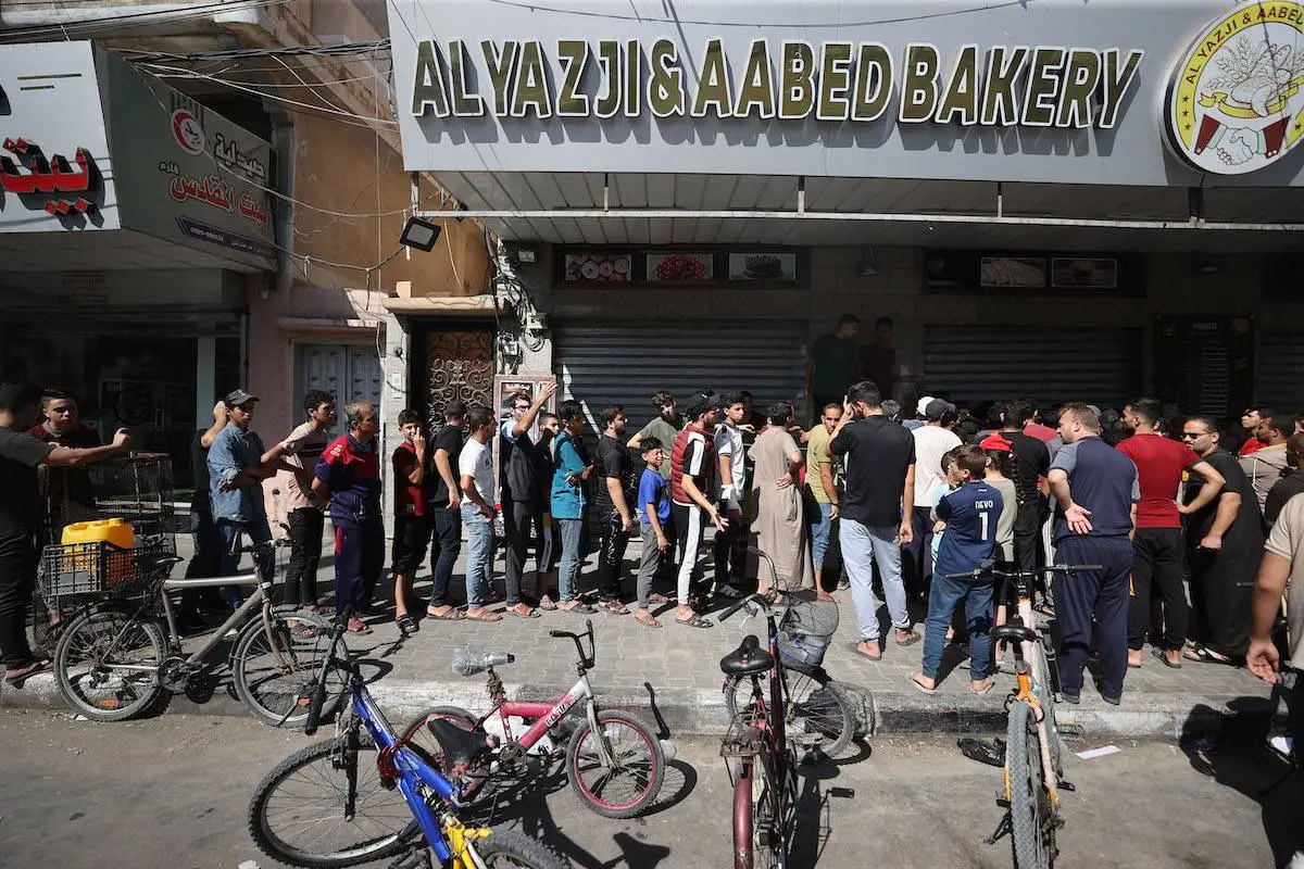Palestinos fazem fila para comprar pão diante da ameaça de fome sob cerco militar israelense, em Khan Yunis, na Faixa de Gaza, em 15 de outubro de 2023 [Mustafa Hassona/Agência Anadolu]
