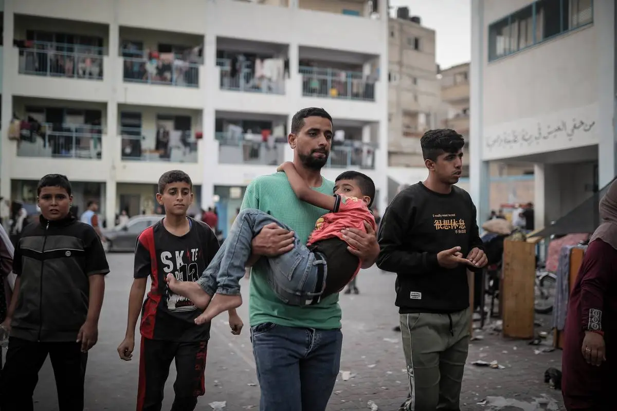 Palestinos que se refugiam em uma escola da UNRWA entram em pânico depois que um ataque aéreo israelense atinge uma casa do outro lado da rua em Khan Yunis, Gaza, em 21 de outubro de 2023. [Belal Khaled - Agência Anadolu]
