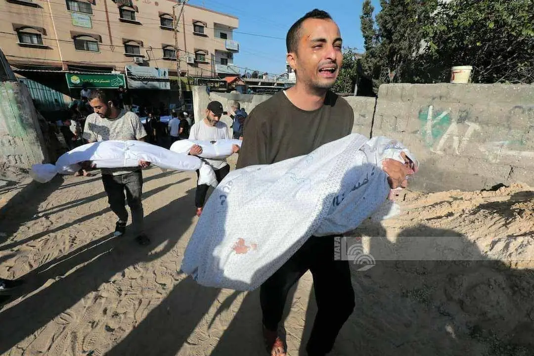 Palestino segura corpo de uma criança na faixa de Gaza bombardeada
