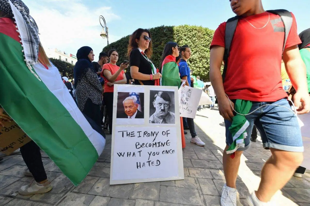 Manifestante com cartaz que mostran os rostos do primeiro-ministro israelense Benjamin Netanyahu e do líder da Alemanha nazista Adolf Hitler durante uma manifestação em solidariedade aos palestinos em Gaza, em Argel, em 19 de outubro de 2023 [AFP via Getty Images]