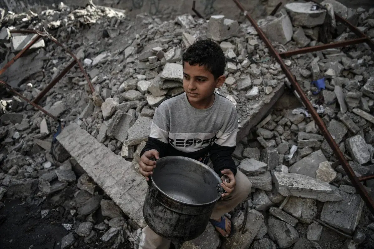 Criança deslocada espera para receber alimento distribuído em Rafah, no sul de Gaza, em 22 de dezembro de 2023 [Abed Zagout/Agência Anadolu]
