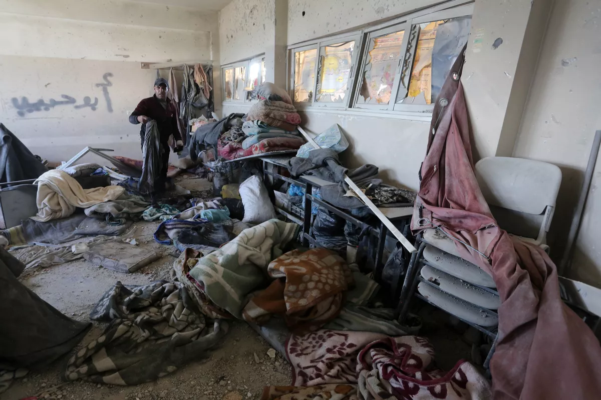 Pessoas evacuam seus pertences após um ataque israelense a uma escola que abriga palestinos deslocados em Deir al-Balah, Gaza, em 31 de dezembro de 2023 [Ashraf Amra – Agência Anadolu]

