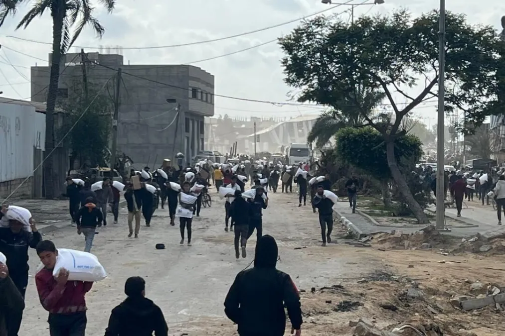 Palestinos correm para obter comida após oito caminhões humanitários entrarem na Cidade de Gaza, em 23 de janeiro de 2024; pouco depois, soldados israelenses abriram fogo contra os civis [Motasem Dalloul/MEMO]
