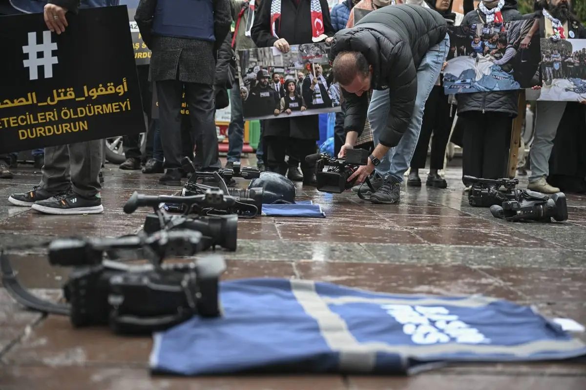 Jornalistas tiram fotos e gravam vídeos do equipamento jornalístico no chão, representando os jornalistas mortos nos ataques israelenses a Gaza, como parte das comemorações do Dia do Trabalhador Jornalista em 10 de janeiro, organizadas pela Plataforma de Solidariedade à Palestina de Ancara no Guvenpark de Ancara, Turquia, em 10 de janeiro de 2024 [Harun Özalp/Anadolu Agency]
