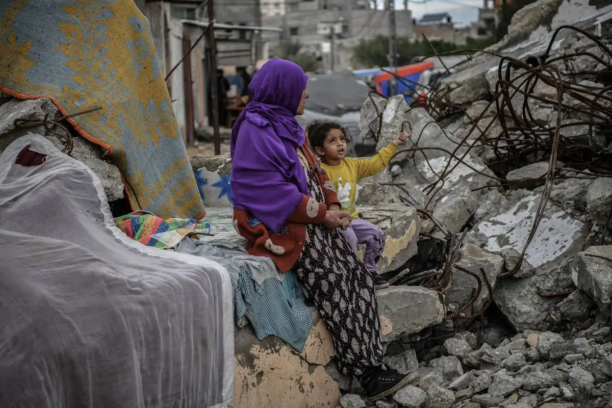 Mãe e filha sentam-se sobre as ruínas de Rafah, no extremo sul de Gaza, em 28 de janeiro de 2024 [Abed Zagout/Agência Anadolu]