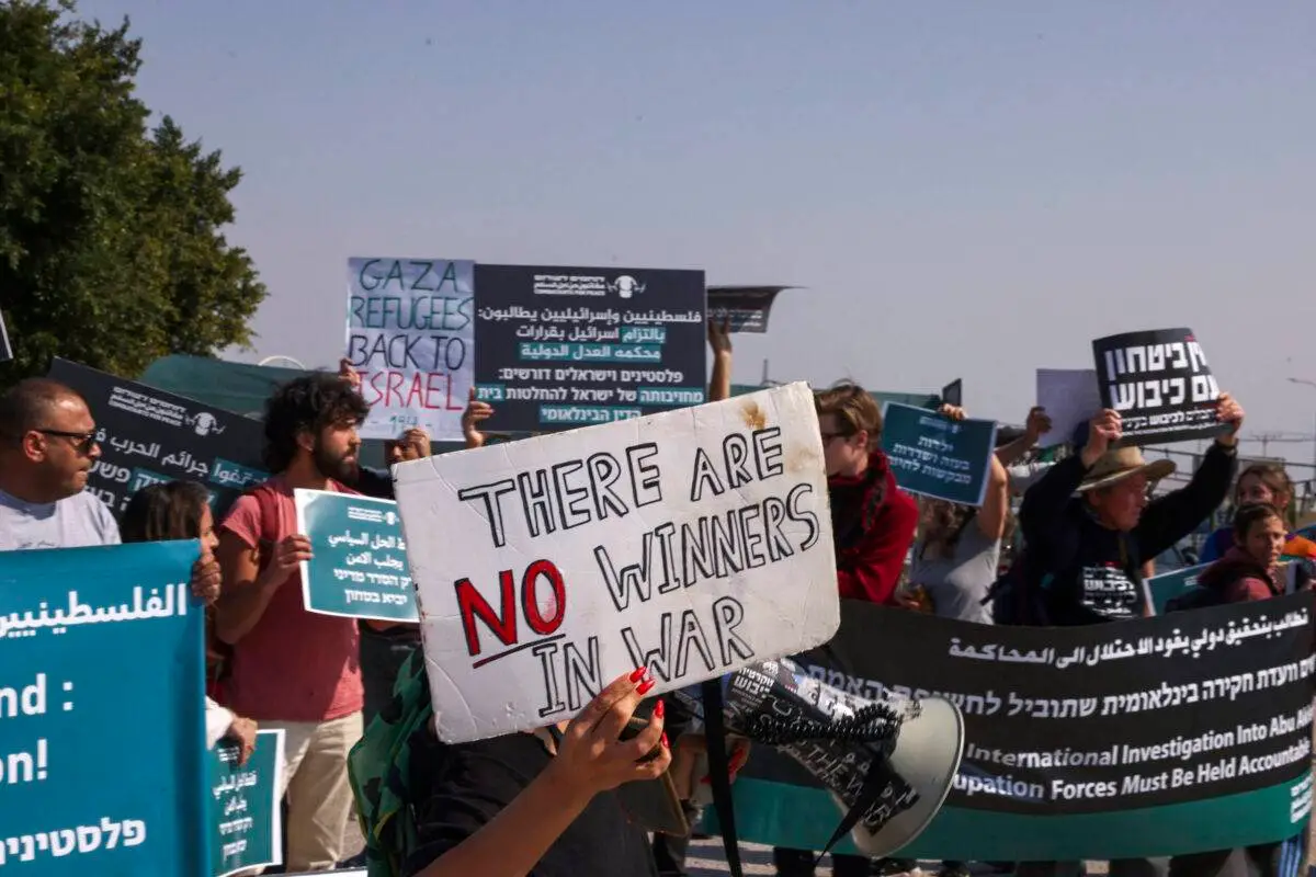 Ativistas israelenses e palestinos levantam faixas enquanto protestam contra a guerra em curso de Israel em Gaza, em um cruzamento da cidade de Jericó, na Cisjordânia ocupada, em 9 de fevereiro de 2024 [Hazem Barder/AFP via Getty Images]
