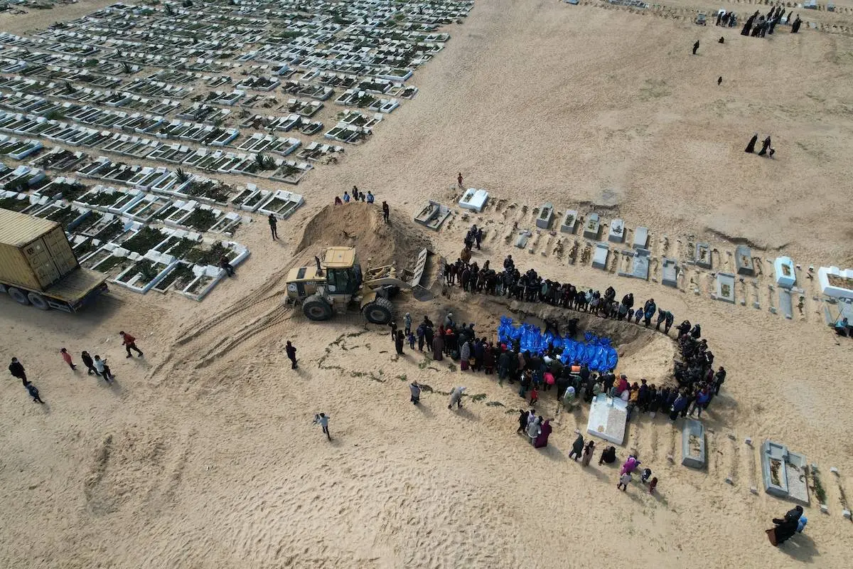Os corpos de 47 palestinos retirados pelas forças israelenses da passagem de fronteira Kerem Shalom são enterrados com a abertura da vala comum após a oração fúnebre em Rafah, Gaza, em 7 de março de 2024 [Mohammed Fayq/Agência Anadolu]
