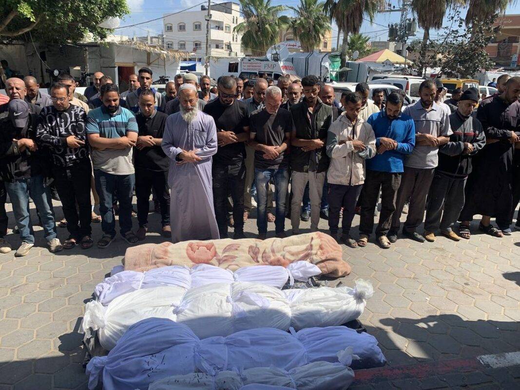 Palestinos diante de uma fila de mortos por um ataque israelense à residência da família Karajah, em Deir al-Balah, em Gaza, 15 de maio de 2024 [Baher Hamed Alnahhal/Agência Anadolu]
