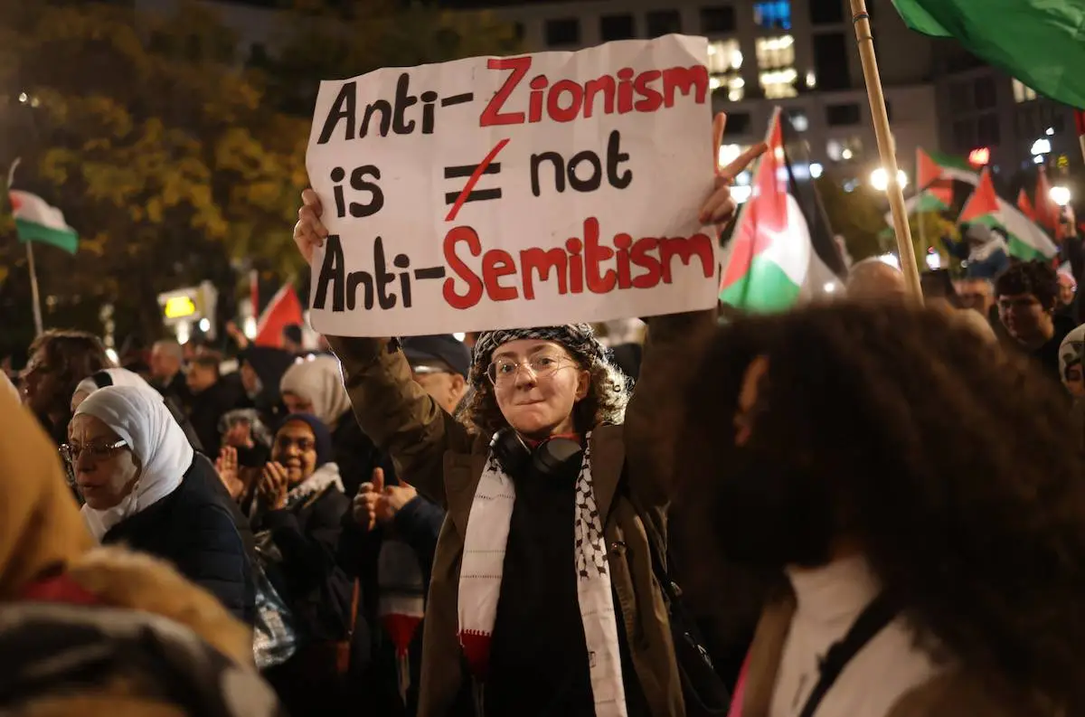 Jovem segura  um cartaz com os dizeres: “Antissionismo não é antissemitismo”, em protesto com bandeiras palestinas que atraiu milhares de participantes em 4 de novembro de 2023 em Berlim, Alemanha. [Sean Gallup/Getty Images]