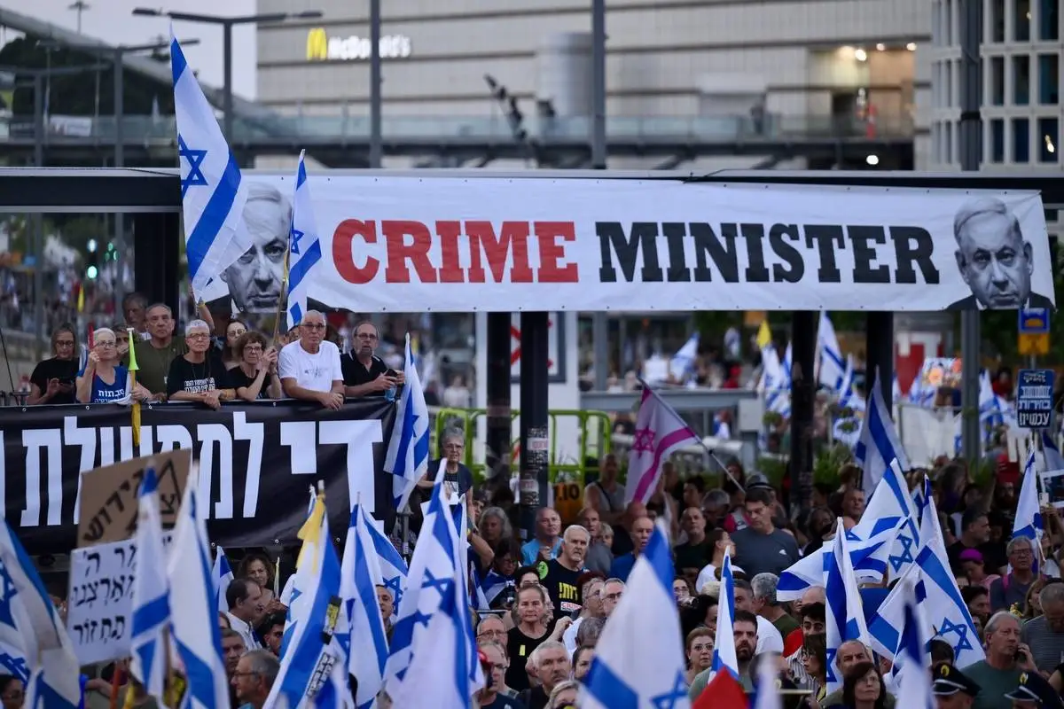 Milhares de pessoas segurando faixas e bandeiras israelenses se reúnem durante uma manifestação para exigir um acordo de troca de reféns com Gaza e a demissão do governo liderado por Benjamin Netanyahu, em Tel Aviv, Israel, em 22 de junho de 2024. [Mostafa Alkharouf/Agência Anadolu].
