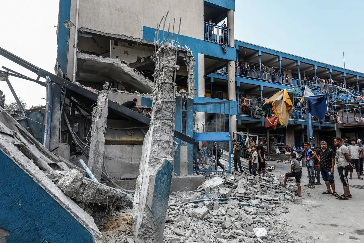 Palestinos e trabalhadores humanitários examinam tendas destruídas por ataques israelenses a uma escola-abrigo da Agência das Nações Unidas para Assistência aos Refugiados da Palestina (UNRWA), no campo de refugiados de Nuseirat, em Deir al-Balah, na Faixa de Gaza, 15 de julho de 2024 [Abed Rahim Khatib/Agência Anadolu]
