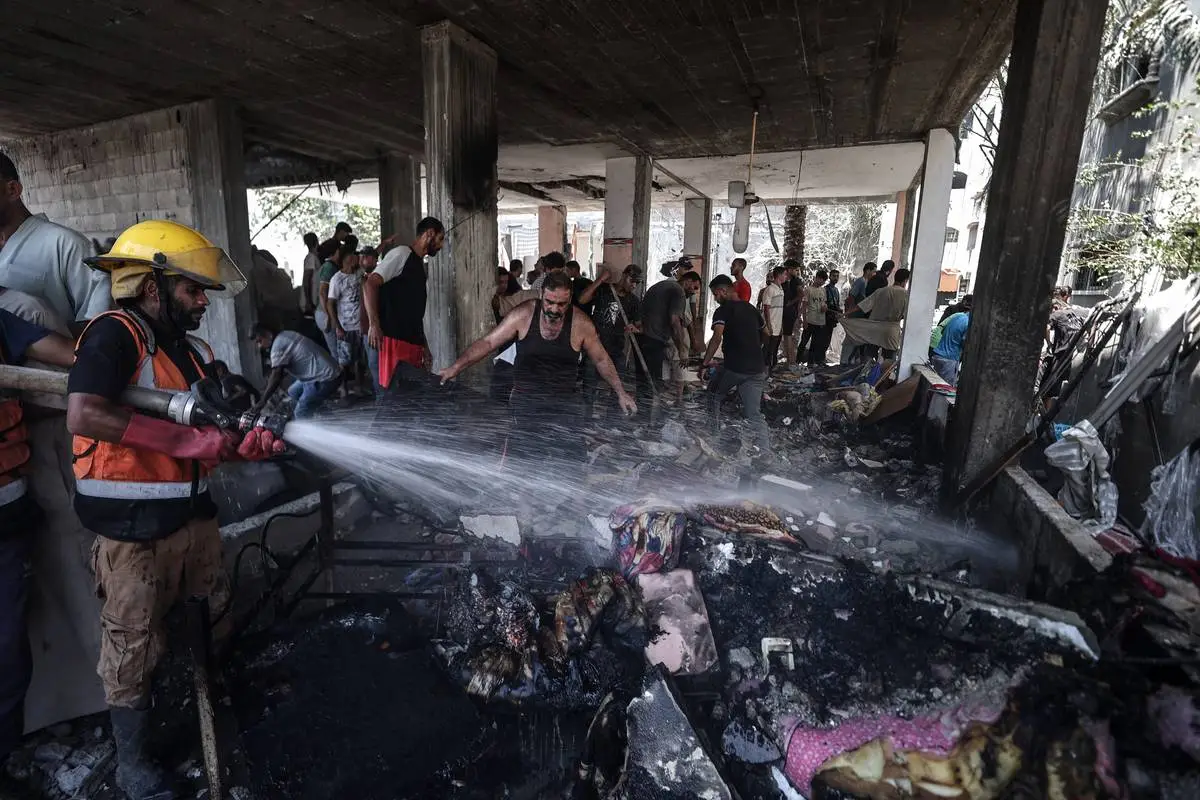 Equipes de defesa civil e palestinos apagam o fogo depois que ataques aéreos israelenses atingiram um prédio residencial em Deir al Balah, Gaza, em 15 de julho de 2024. [Ali Jadallah/Agência Anadolu].
