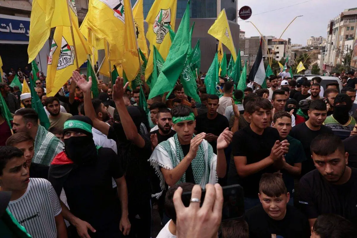 Pessoas agitam as bandeiras dos movimentos palestinos Hamas e Fatah, durante uma marcha de solidariedade com os palestinos da Faixa de Gaza, na cidade ocupada de Hebron, na Cisjordânia, em 27 de outubro de 2023 [HAZEM BADER/AFP via Getty Images]
