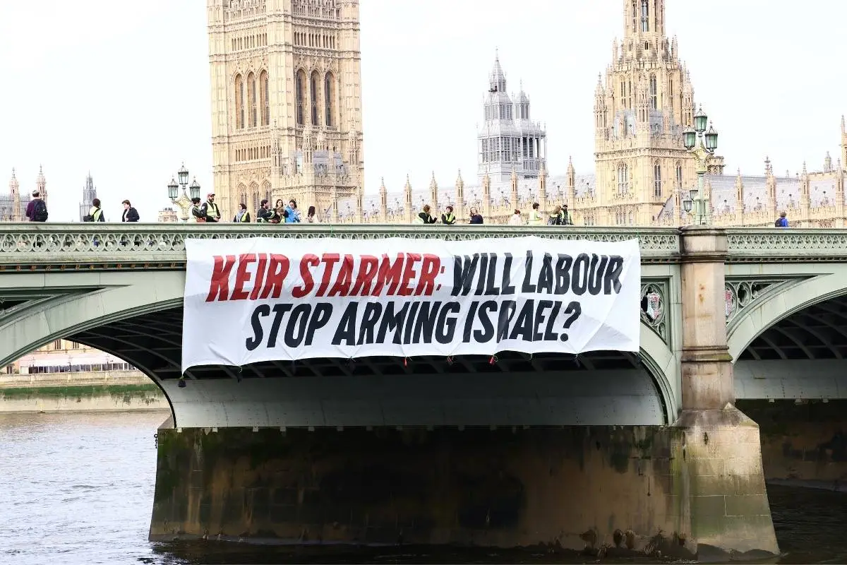 Ativistas deixam cair uma faixa da ponte de Westminster, pedindo ao líder trabalhista Keir Starmer que diga que acabará com a venda de armas a Israel se ele se tornar primeiro-ministro, em 3 de junho de 2024, em Londres, Reino Unido [Luca Marino]
