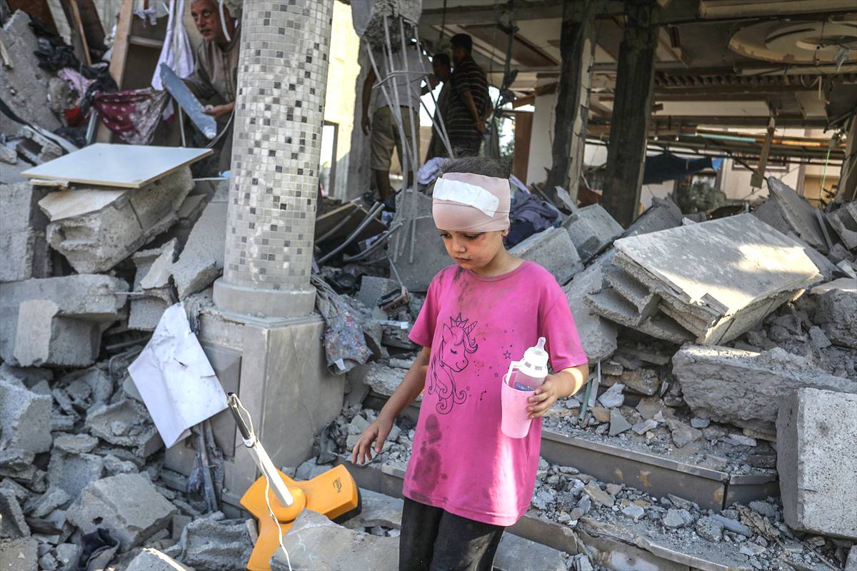 Criança ferida caminha entre os escombros deixados por ataques israelenses ao campo de refugiados de Nuseirat, na Faixa de Gaza sitiada, 14 de agosto de 2024 [Abed Rahim Khatib/Agência Anadolu]
