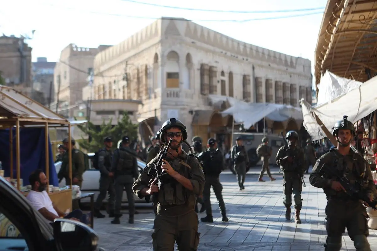 Colonos israelenses sob escolta militar marcham em Hebron (Al-Khalil), na Cisjordânia ocupada, em 7 de setembro de 2024 [Mamoun Wazwaz/Agência Anadolu]
