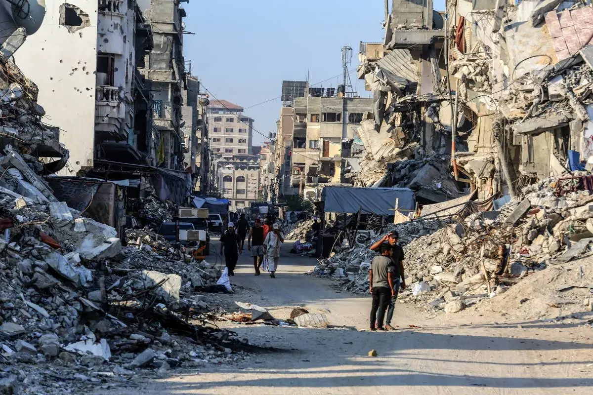 Palestinos caminham perto dos destroços de prédios destruídos enquanto a escala de destruição causada pelos ataques israelenses vem à tona após a retirada do exército israelense em Khan Yunis, Gaza, em 29 de setembro de 2024. [Abed Rahim Khatib/Agência Anadolu]
