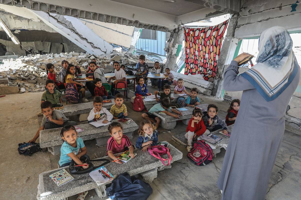 Professores voluntários continuam a ensinar crianças em uma sala de aula destruída na Escola Tabariya, que foi em grande parte destruída em um ataque do exército israelense. [Abed Rahim Khatib/Agência Anadolu]
