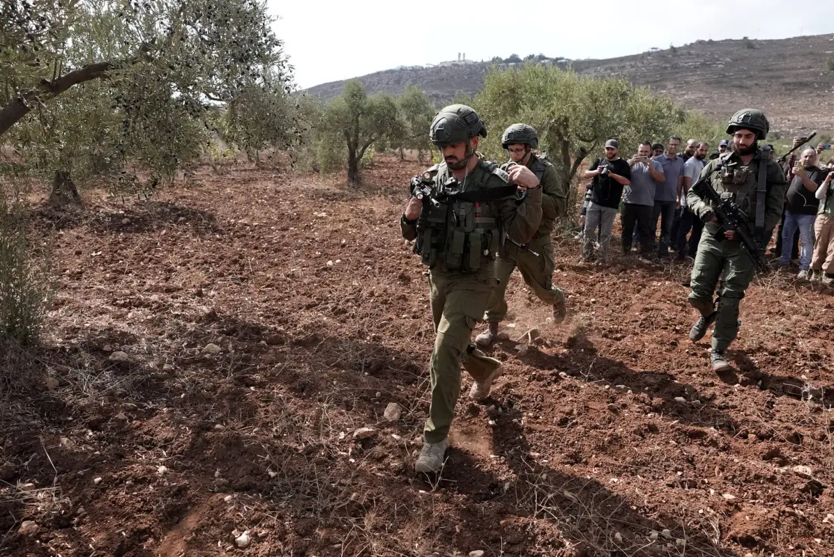 Soldados israelenses invadem plantação de  agricultores palestinos que continuam a colher suas oliveiras apesar dos ataques israelenses na aldeia de Qasra e ativistas estrangeiros que os apoiam no sudeste de Nablus, Cisjordânia, em 15 de outubro de 2024 [Issam H.s. Alasmar/Anadolu Agency]
