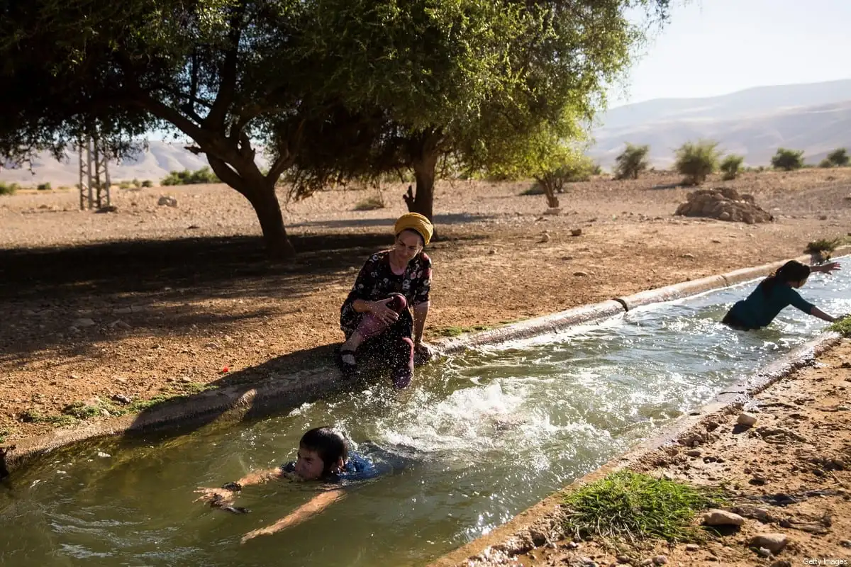 Uma família de colonos judeus nada na água da fonte natural de Ein Al-Auja na Cisjordânia ocupada do Vale do Jordão em 24 de junho de 2020 [Amir Levy/Getty Images]
