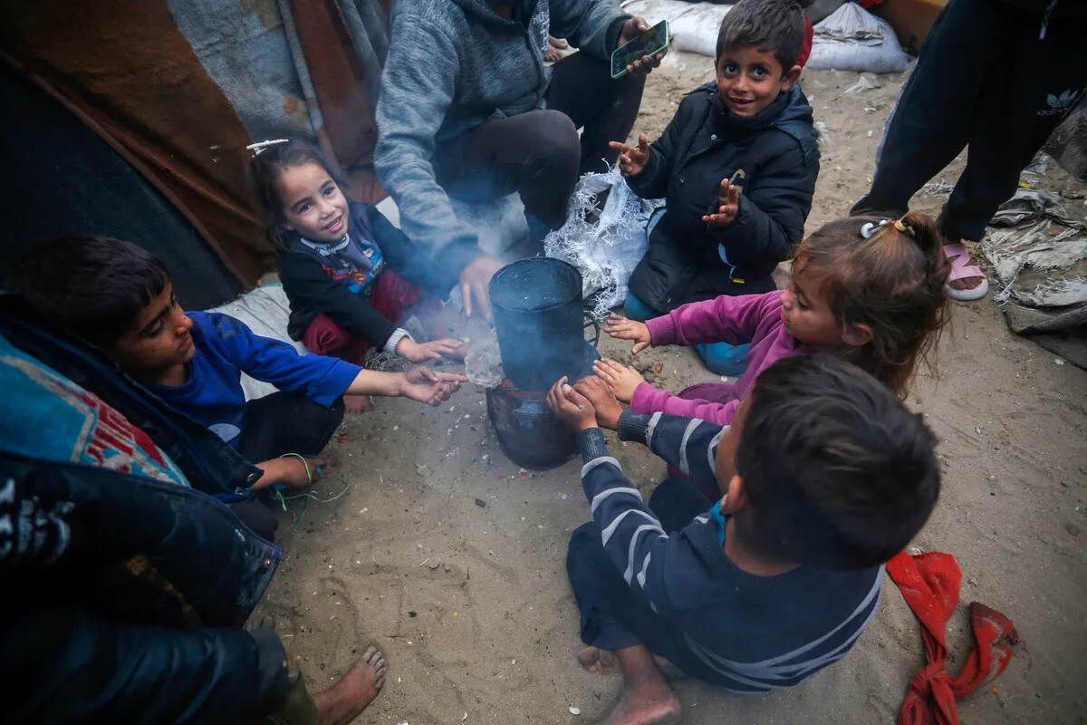Palestinos tentam se aquecer ao redor de uma fogueira durante a vida cotidiana enquanto os ataques israelenses continuam em Deir al-Balah, Gaza, em 26 de dezembro de 2024 [Ashraf Amra/Agência Anadolu]