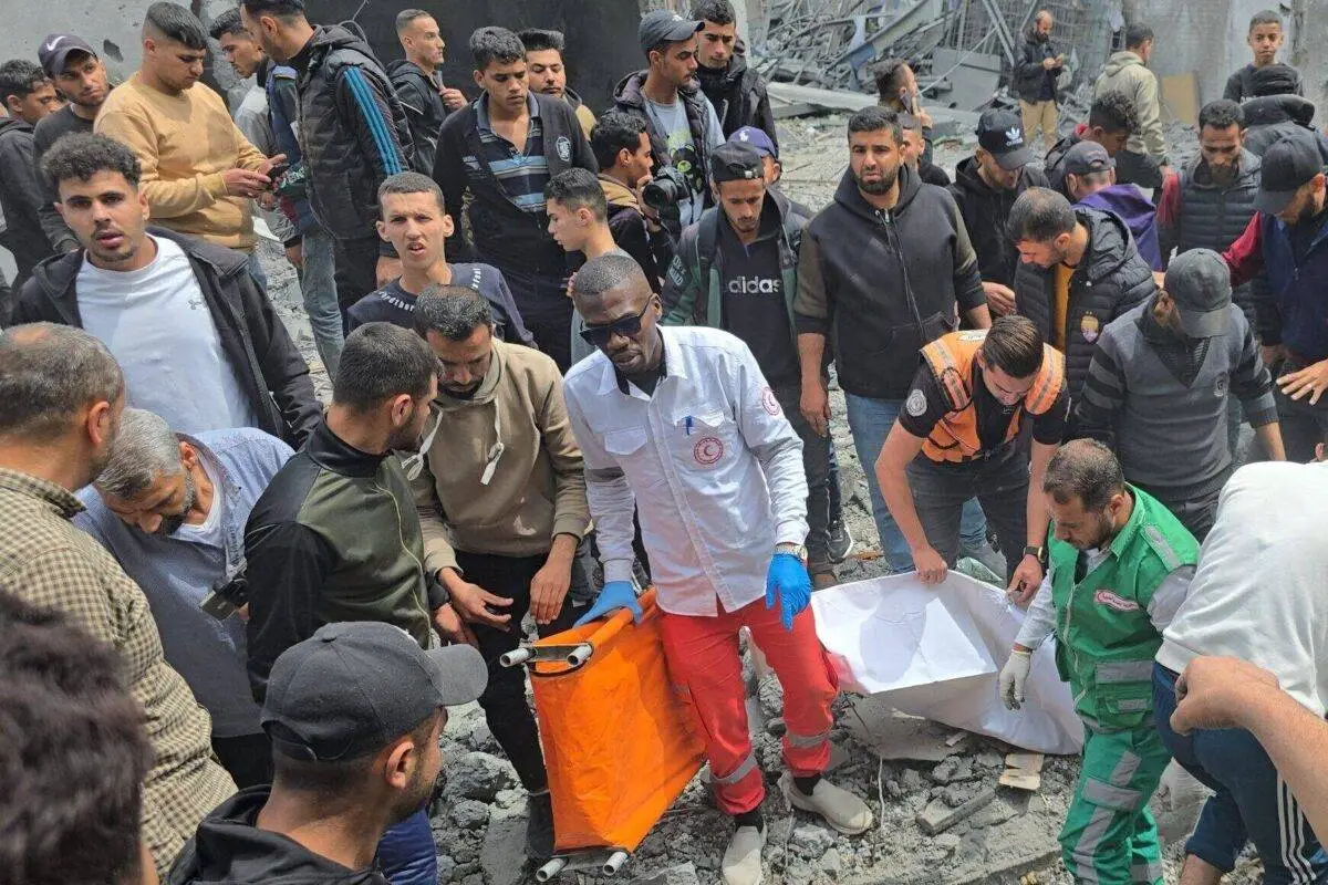 Moradores e equipes de defesa civil realizam uma operação de busca e resgate entre os escombros de um prédio que desabou após um ataque israelense ao prédio da prefeitura em Deir Balah, Gaza, em 13 de abril de 2025 [Ashraf Amra/Agência Anadolu]