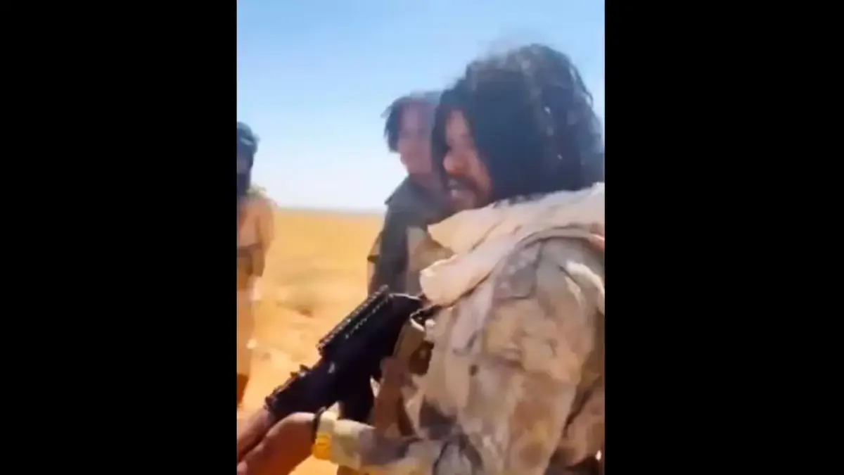 Um homem que parece ser o comandante das RSF, Abu Lulu, aponta uma arma para homens detidos antes de atirar neles (mídias sociais)