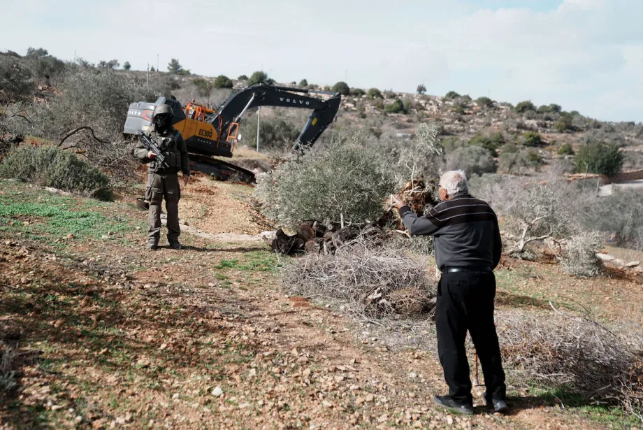 Soldados israelenses observam enquanto veículos de construção israelenses destroem terras agrícolas e arrancam oliveiras centenárias na vila de Karyut, ao sul da cidade de Nablus, na Cisjordânia, em 8 de dezembro de 2025. [Issam Rimawi – Agência Anadolu]