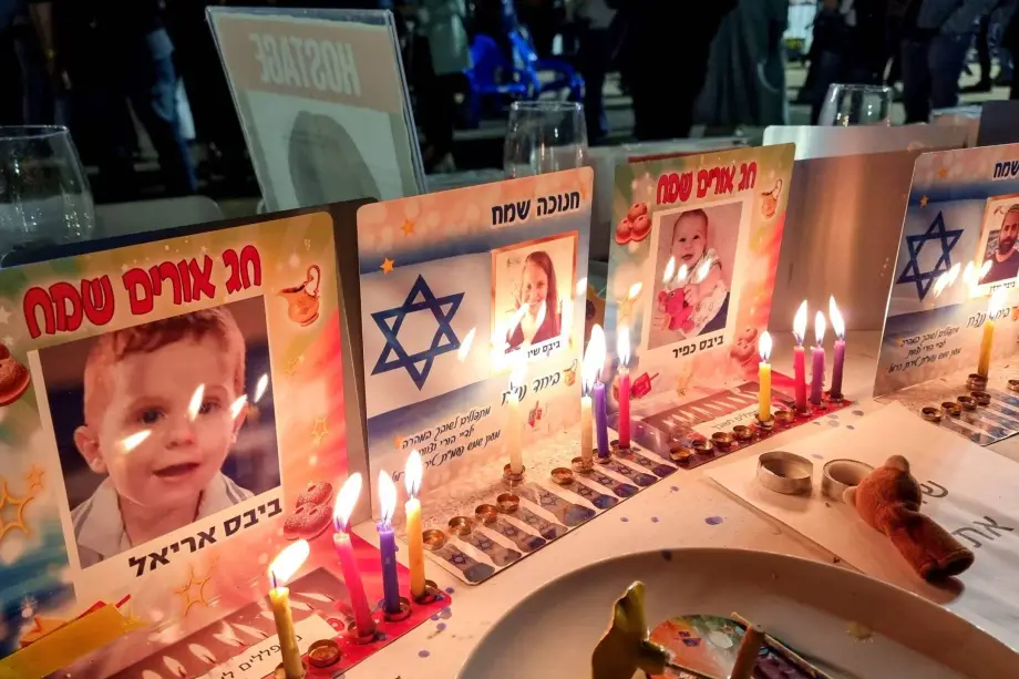 Velas de Hanukkah são acesas nos lugares reservados na mesa festiva para a família Bibas, em 9 de dezembro de 2023, em Tel Aviv, Israel [David Silverman/Getty Images]