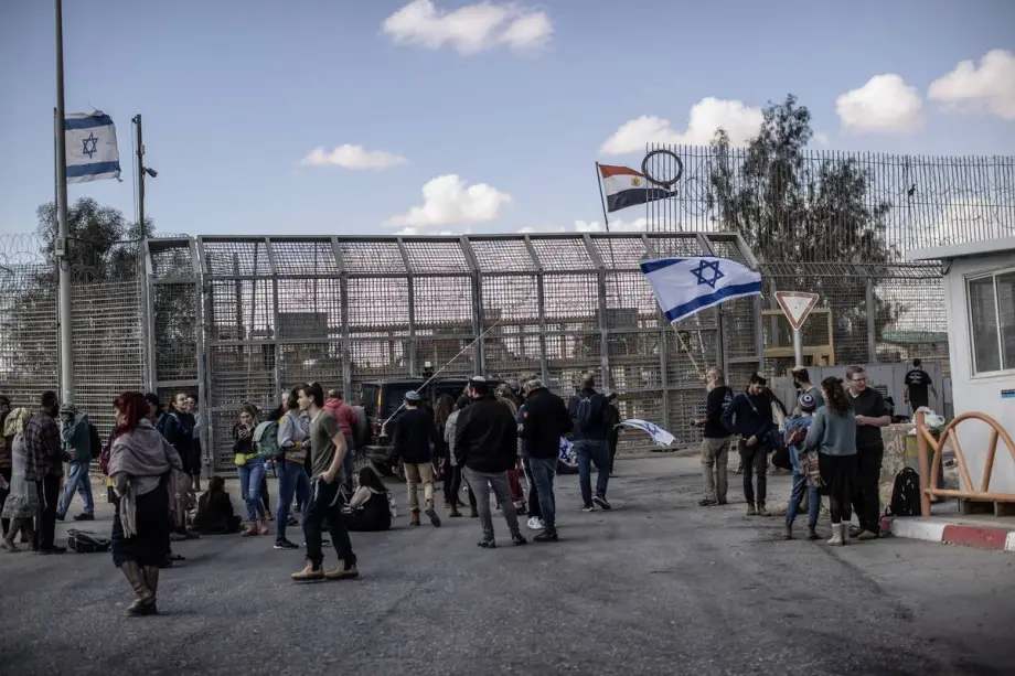 Um grupo de colonos judeus ativistas, segurando uma bandeira israelense, se reúne em frente à passagem de fronteira de Nitzana, na fronteira com o Egito, para impedir a entrada de ajuda humanitária enviada a Gaza, em Nitzana, Israel, em 14 de fevereiro de 2024. [Mostafa Alkharouf – Agência Anadolu]