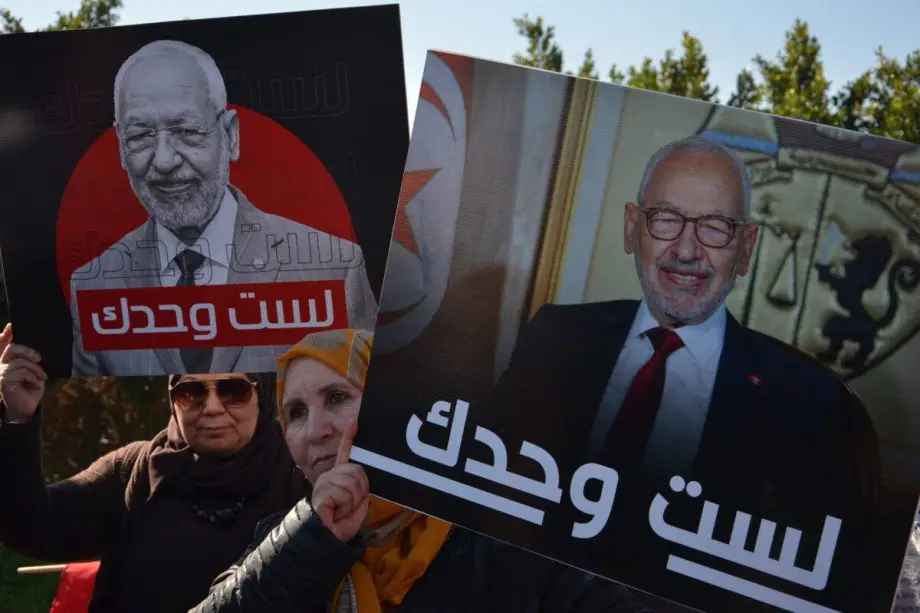 Uma mulher segura uma placa com a imagem de Rached Ghannouchi em apoio ao líder do Movimento Ennahda, Rached Ghannouchi, em frente ao Posto Judicial Antiterrorismo em Charguia, Túnis, Tunísia, em 21 de fevereiro de 2023 [Hasan Mrad/DeFodi Images via Getty Images]