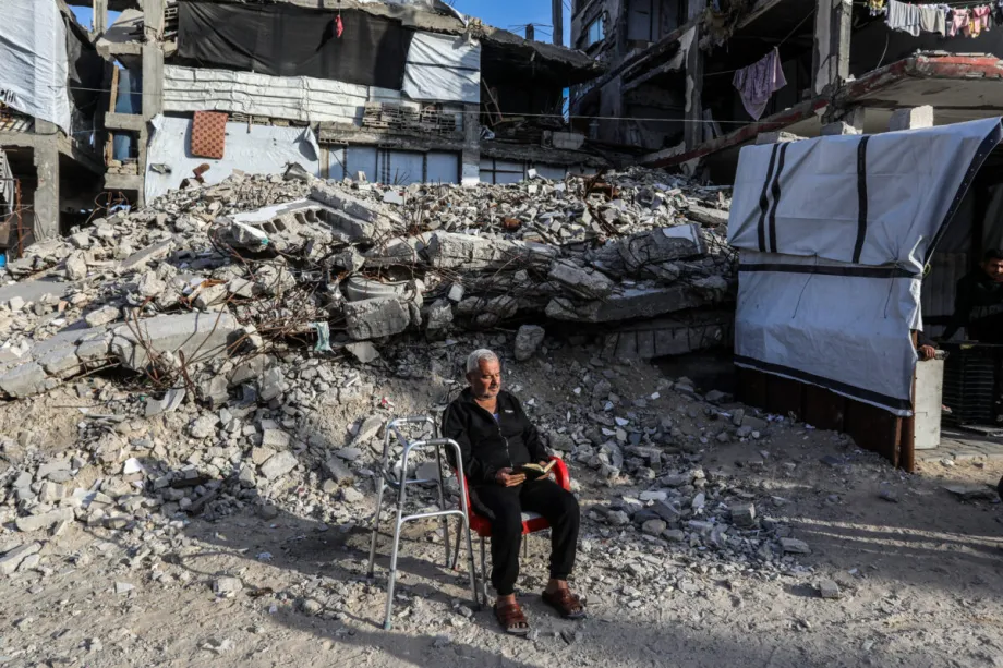 Um palestino lê o Alcorão Sagrado apesar do frio para continuar as orações do Ramadã em frente às ruínas de Khan Yunis, Gaza, em 2 de março de 2026. [Abed Rahim Khatib – Agência Anadolu]