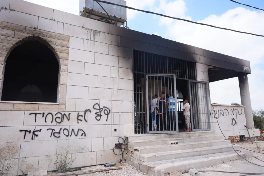 Grafites em hebraico com mensagens contra palestinos são vistos nas paredes externas da Mesquita Al-Rahmah após uma suposta tentativa de incêndio durante uma incursão de colonos israelenses na aldeia de Qusra, perto de Nablus, na Cisjordânia, Palestina, em 26 de julho de 2026. [Issam Rimawi – Agência Anadolu]