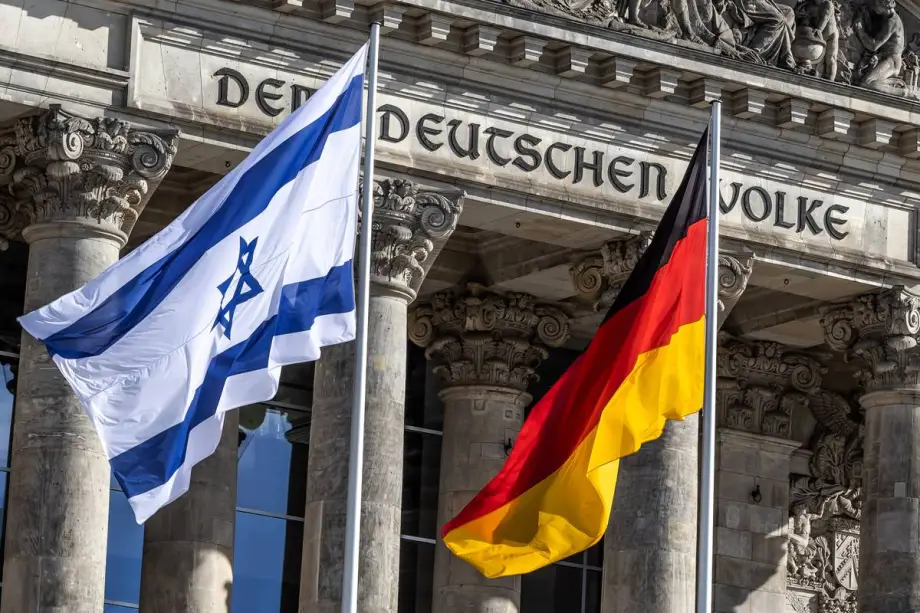 As bandeiras de Israel e da Alemanha são exibidas em frente ao prédio do Parlamento alemão, em Berlim. [Foto via Getty Images]
