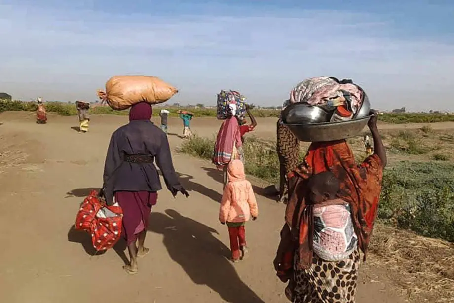 Mulheres sudanesas deslocadas carregam seus pertences enquanto caminham em direção a um campo próximo à cidade de Tawila, em Darfur do Norte, em 11 de fevereiro de 2025 [MARWAN MOHAMED/AFP via Getty Images]