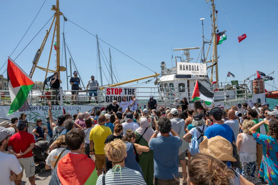 Pessoas se reúnem ao redor do navio da Flotilha da Liberdade, “Handala”, antes da partida da embarcação com destino a Gaza, em um porto de Siracusa, na Sicília, sul da Itália, em 13 de julho de 2025. [GIOVANNI ISOLINO/AFP via Getty Images]